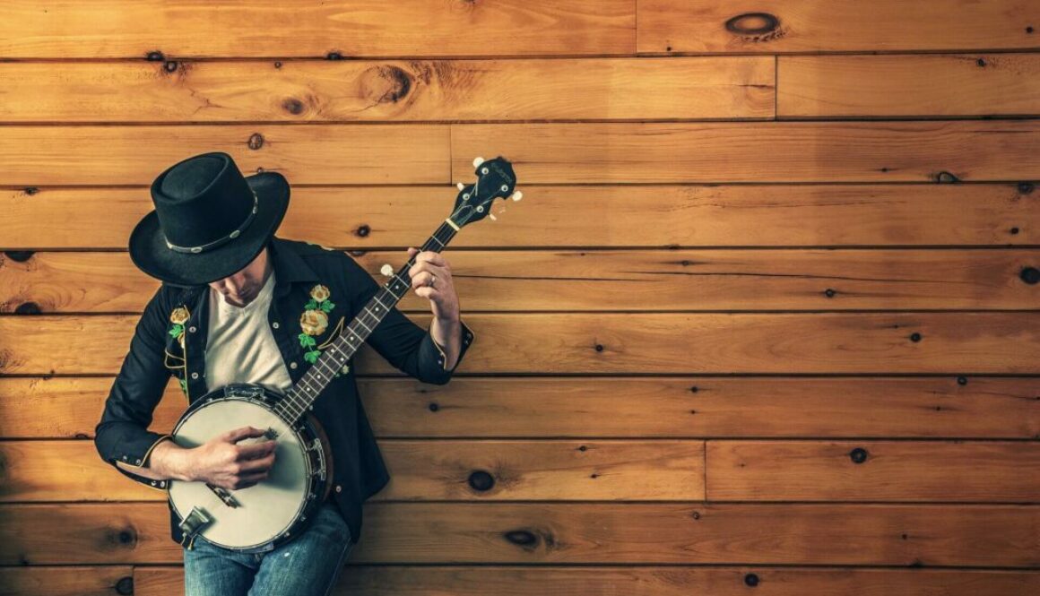 musiker med gitarr lutar sig mot en vägg
