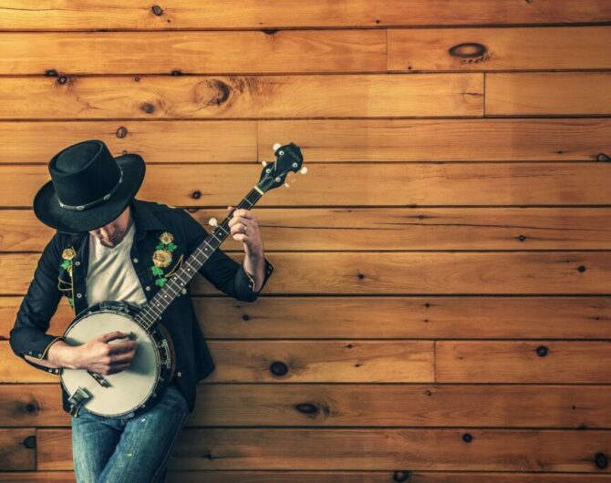 musiker med gitarr lutar sig mot en vägg